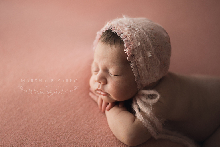 newborn wearing pink bonnet